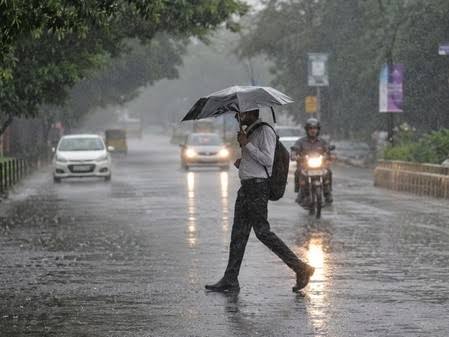 बारिश के दौरान भारत के एक शहर की सड़क पर लोगों और वाहनों की आवाजाही
